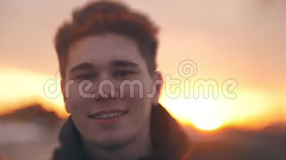 年轻微笑的男人看日落时相机的肖像视频的预览图