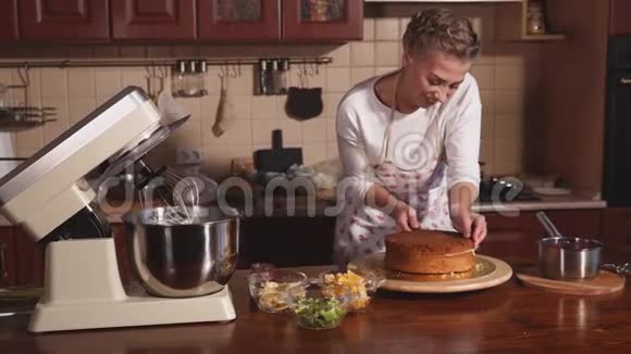一个年轻的金发女孩正在一层一层地切饼干坯做蛋糕视频的预览图