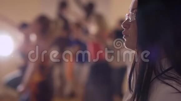 戴眼镜的年轻女子看跳舞的人视频的预览图