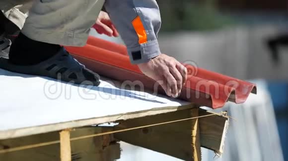 用电钻将红色金属瓷砖安装在木屋上将穿工作服的人进行特写剪辑房屋建筑视频的预览图