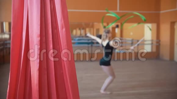 年轻迷人的女子训练与绿色丝带体操运动在工作室与镜子不专注视频的预览图