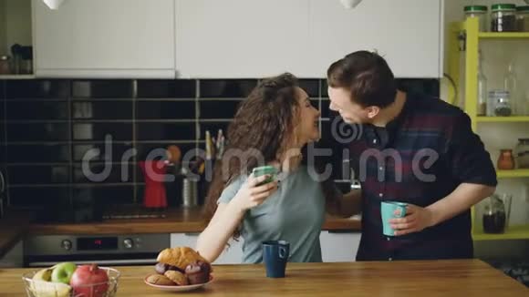年轻快乐的白种人夫妇早上在现代厨房的爱会上一起吃早餐他们视频的预览图
