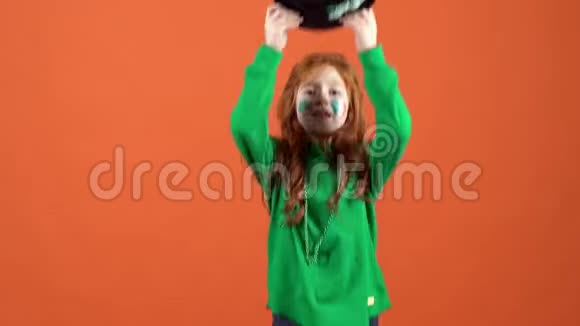 女孩红发庆祝圣帕特里克天橙色背景戴帽子视频的预览图