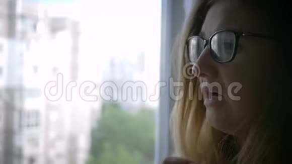 家中窗户附近戴眼镜的神经紧张的精神病患者视频的预览图