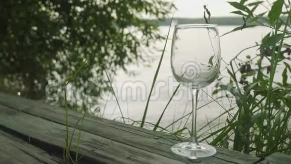 恩蒂杯里装满了白酒湖上的旧木墩上有玻璃视频的预览图