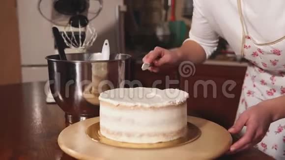 糖果女人正用刀片将蛋糕上的一层抹上鲜奶油视频的预览图