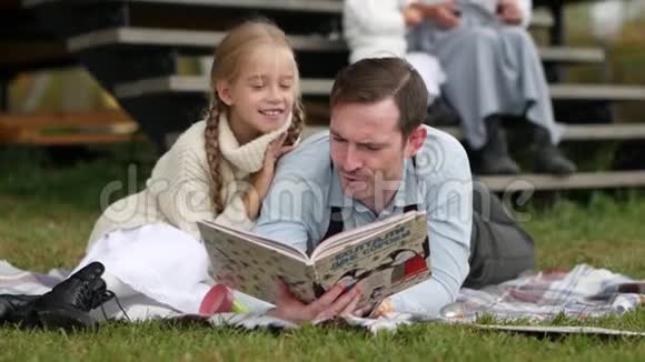 小女孩坐着拥抱她的父亲读一本书视频的预览图