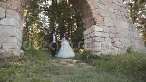 幸福的新婚夫妇面带笑容地走在城堡里慢慢地视频的预览图