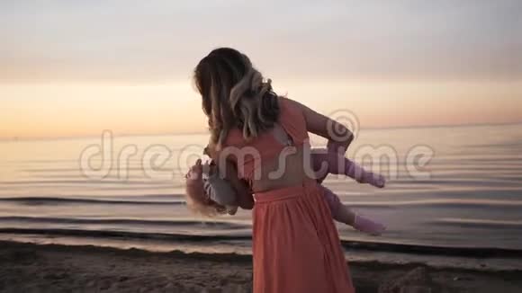 日落时分妈妈和女儿笑着沿着海滨散步视频的预览图