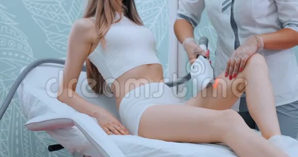年轻女性穿着白色浴袍在美容师诊所进行激光脱毛手术动作缓慢医生去掉头发视频的预览图