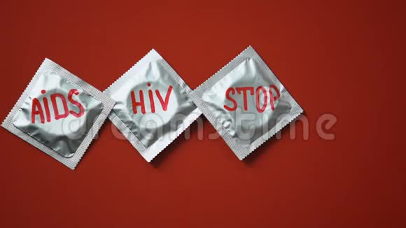 预防艾滋病在红色背景下用红丝带在避孕套上视频的预览图
