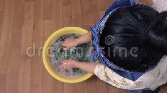 女人在地上的碗里洗衣服视频的预览图