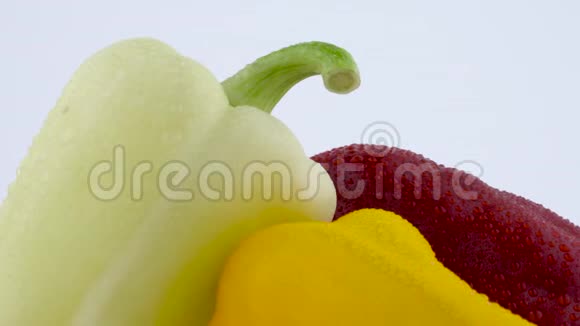 超级接近三个甜椒白色黄色和红色的水滴在转盘上旋转视频的预览图