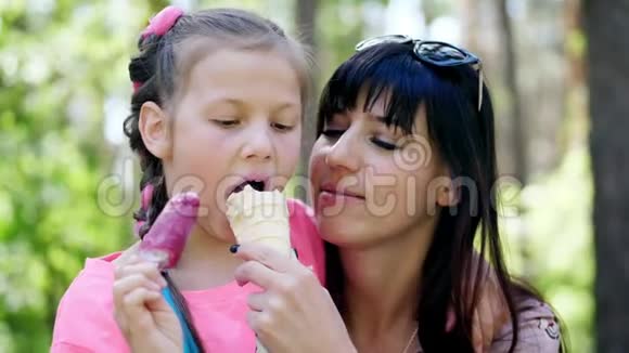 八岁的漂亮女孩金发有雀斑她的母亲一个黑发女人吃着华夫饼杯里的白色冰淇淋视频的预览图