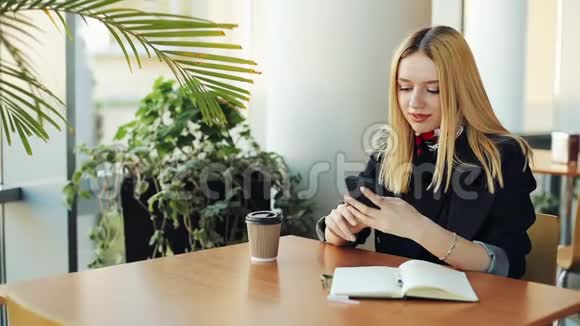 坐在咖啡馆里的女青年在她的智能手机里键入一些东西视频的预览图