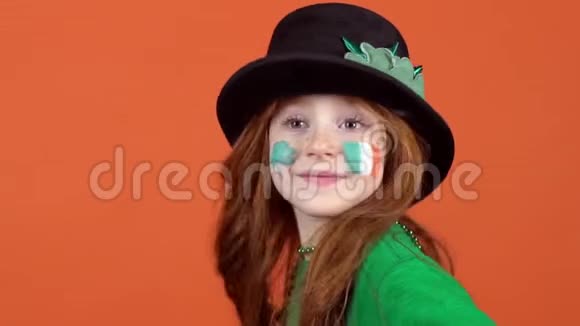 女孩红发庆祝圣帕特里克天橙色背景微笑嬉戏视频的预览图