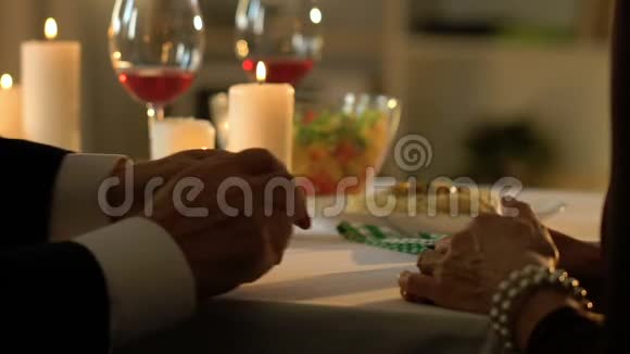 老人轻轻抚摸女性的双手在餐厅浪漫约会特写镜头视频的预览图
