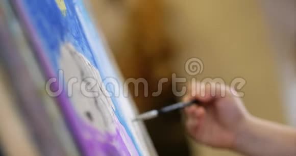 年轻的艺术家的手小女人艺术家用画笔描绘画布坐着一张桌子画在画布上流程视频的预览图