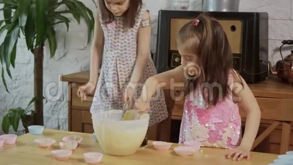 两个小女孩把奶油放在模具上做纸杯蛋糕视频的预览图