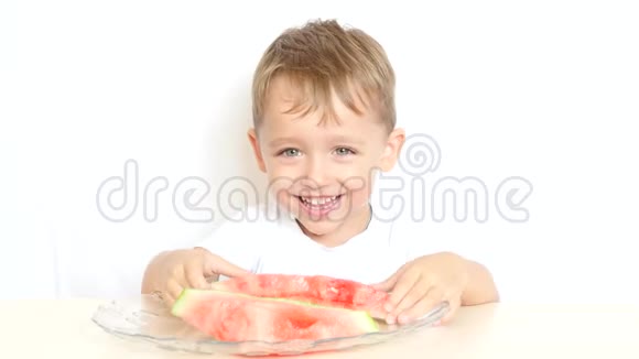 一个快乐的孩子坐在一张桌子旁吃着白色背景的西瓜吃着一顿快乐的饭视频的预览图