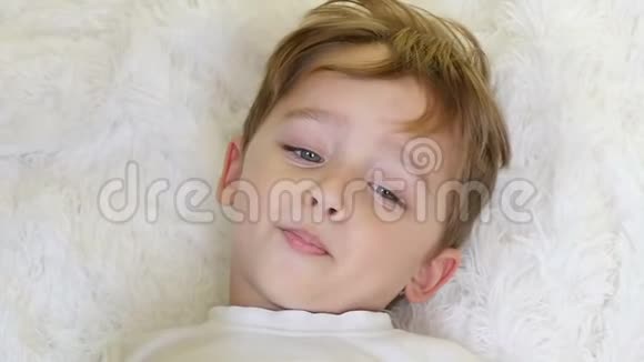 一个小孩躺在白色的毯子上用缓慢的速度看着镜头视频的预览图