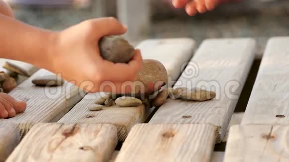 夏天一个孩子在海边的木架上玩石头特写镜头视频的预览图