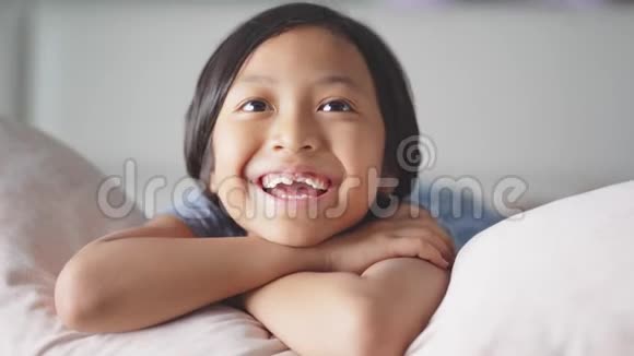 可爱的无牙女孩在卧室看电视视频的预览图