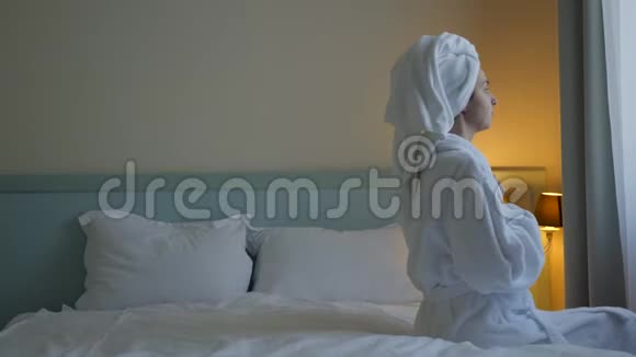 穿着白色浴袍的女孩倒在床上视频的预览图