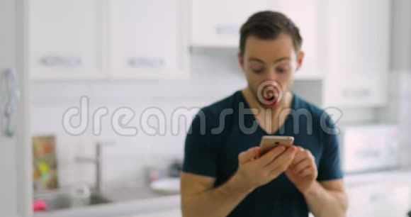 一个男人在家里展示着空的绿色智能手机屏幕惊喜不已视频的预览图