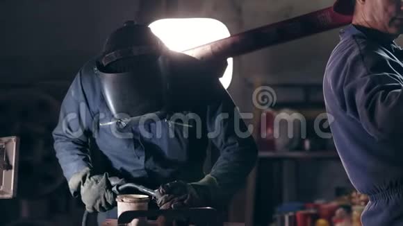 机械机库防护工作服的工人焊接头盔的工人把两个金属件连接在一起视频的预览图