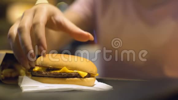 从餐桌上拿芝士汉堡的女人在快餐店吃晚餐视频的预览图
