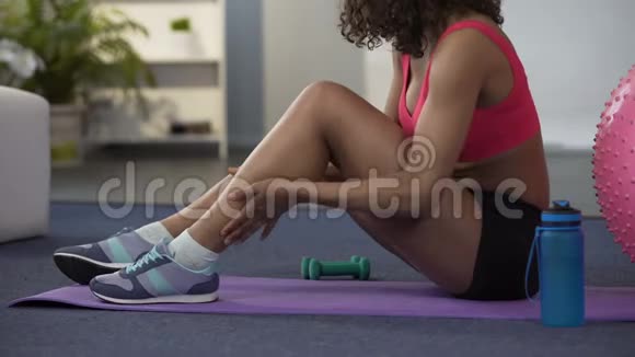 穿着健身服的女孩坐在地板上按摩狭窄的腿和肌肉视频的预览图