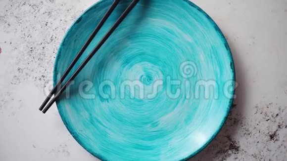 青绿色手工彩绘陶瓷盘子旁边放木筷视频的预览图
