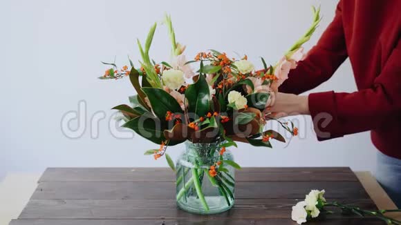 女花匠把花放在玻璃花瓶里做了一个新的花安排从盒子里摘鲜花的女人视频的预览图