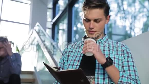 男子读书笔记和在校园大厦喝咖啡视频的预览图