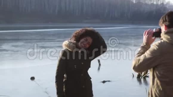 男人在冰冻的湖边给女人拍照视频的预览图