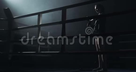 年轻女子用黑色拳击把手裹在黑暗的戒指里剪影拳击概念视频的预览图