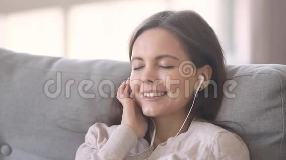 女人躺在沙发上通过耳机听音乐视频的预览图
