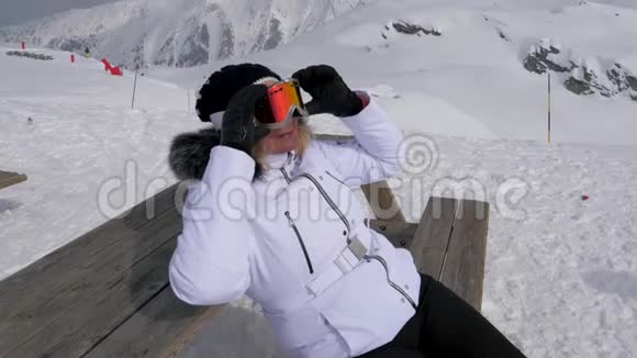 坐在长凳上的女滑雪者在山上休息和晒太阳视频的预览图