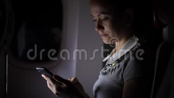 晚上客机上的女商人在智能手机上发短信视频的预览图