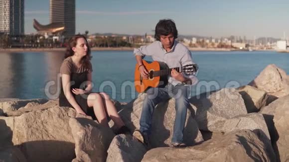 一对乐队成员在海滩边弹吉他唱歌视频的预览图