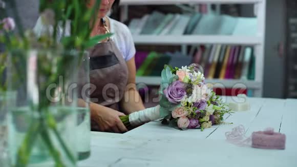 在花艺设计工作室专业的花艺师用丝带布置婚礼花束视频的预览图