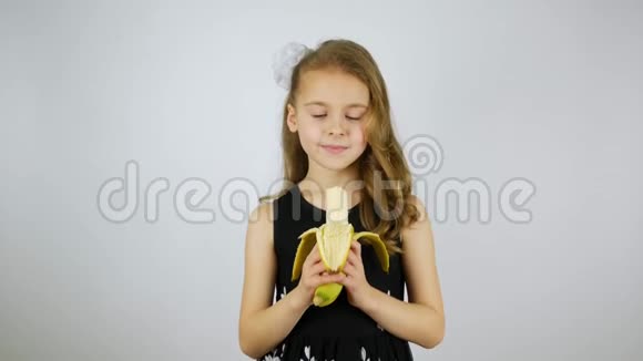 剥皮和吃一根大香蕉一个漂亮的小女孩咬着一根香蕉微笑着视频的预览图