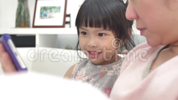 快乐的亚洲家庭母女在电话里看着微笑着扩展视频的预览图