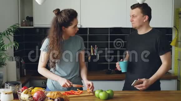 年轻的白种人夫妇在智能手机上听音乐在家厨房的餐桌旁跳舞美女是视频的预览图