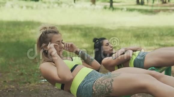 健身妇女在城市公园做仰卧起坐美丽的女性在户外运动视频的预览图
