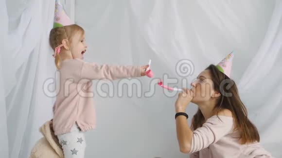 小金发女孩和她的母亲吹着喜庆的喇叭视频的预览图