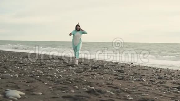 疯狂的女人穿着吉古鲁米的独角兽装在海滩上奔跑视频的预览图