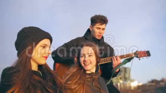 快乐的朋友在日落时分用吉他在户外唱歌视频的预览图