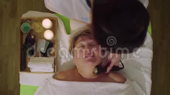 年轻的中国医生给一位老年妇女做美容按摩视频的预览图